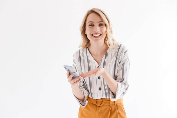 Photo of caucasian blond woman wearing casual clothes smiling at camera and pointing on smartphone - Фото, зображення