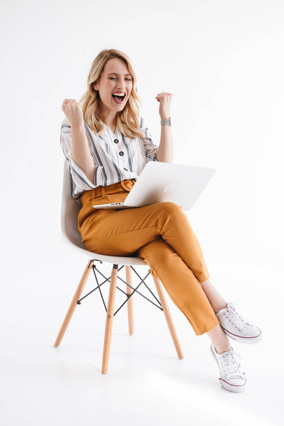 Photo of european happy woman wearing casual clothes using laptop while sitting in chair - Фото, зображення