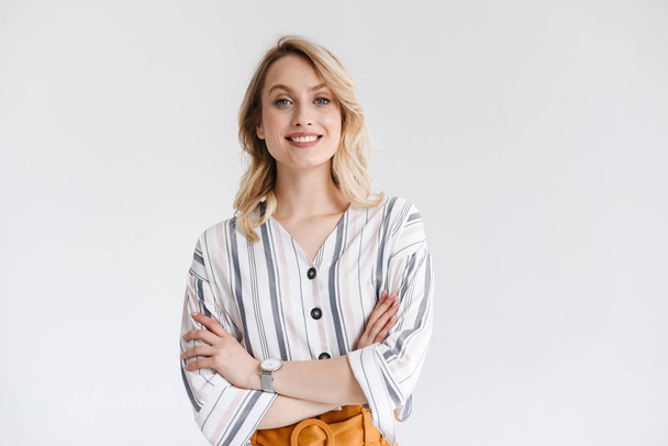 Portrait of blond young woman wearing casual clothes smiling at camera with arms crossed - 写真・画像