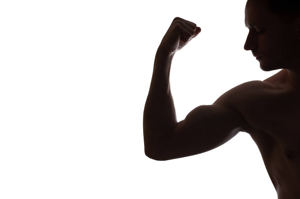 Muscular jovem fisiculturista demonstra seu bíceps em branco backg
 - Foto, Imagem