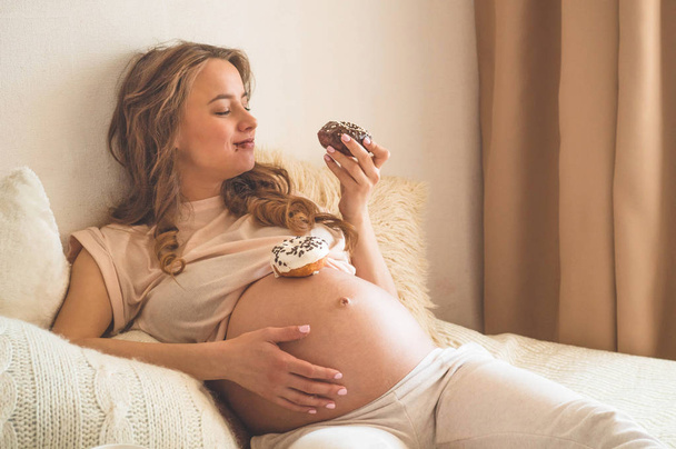 Pregnancy and nutrition. Pregnant woman enjoying donuts and tea in bed, free space. Concept of expectation and health - Foto, Bild