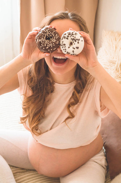 Raskaus ja ravitsemus. Raskaana oleva nainen nauttii donitseja ja teetä sängyssä, vapaata tilaa. Odotuksen ja terveyden käsite
 - Valokuva, kuva