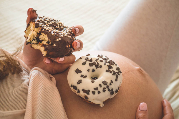 Schwangerschaft und Ernährung. Schwangere genießen Donuts und Tee im Bett, freier Platz. Konzept der Erwartung und Gesundheit - Foto, Bild