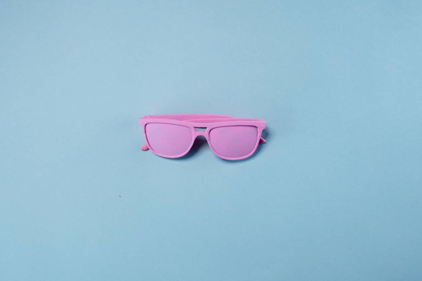 Pink glass lie on pastel blue background. Minimal summer concept - Фото, изображение