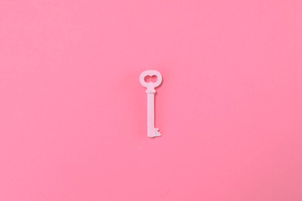 Pink key lie on pastel pik background. Minimal summer concept. - Фото, изображение