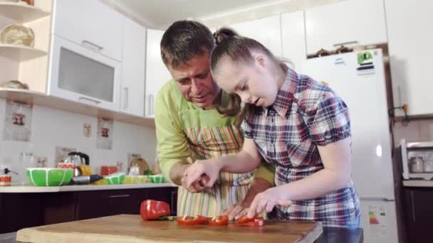 Ένας πατέρας διδάσκει την κόρη του με σύνδρομο Down πώς να κόψει τα λαχανικά. - Πλάνα, βίντεο