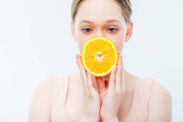adolescente sosteniendo maduro naranja medio en frente de boca aislado en blanco
 - Foto, Imagen
