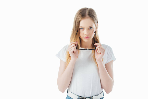 cheerful teenage girl holding glasses and looking at camera isolated on white - Foto, afbeelding