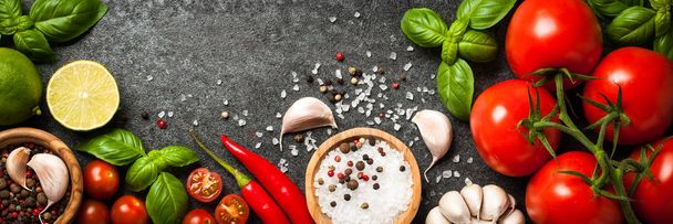 Tomatoes, spices and basil leaves on black background - Фото, изображение