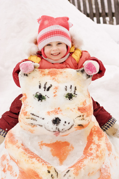 Happy baby sitting on a snowman - Zdjęcie, obraz