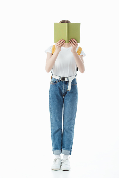 schoolgirl with backpack holding book in front of face isolated on white - Foto, Imagen