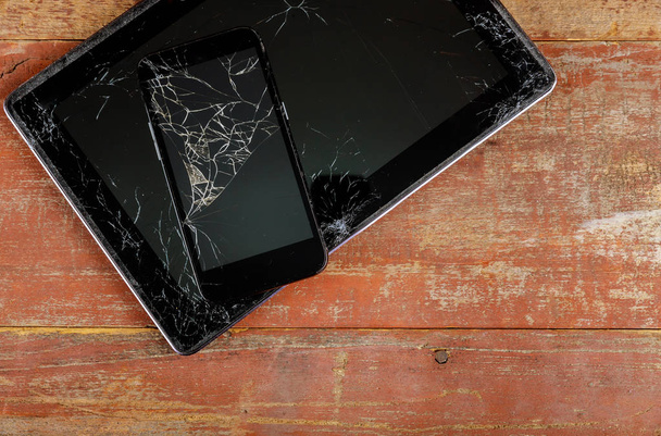 Tableta y teléfono inteligente con pantalla de vidrio roto en el fondo de madera
 - Foto, Imagen