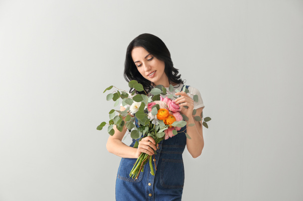 Portrait of beautiful woman with bouquet on light background - Photo, image