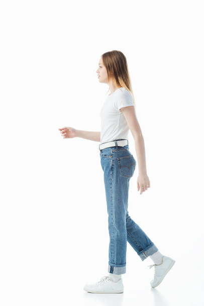 side view of teenage girl in blue jeans and white t-shirt walking isolated on white - Foto, immagini
