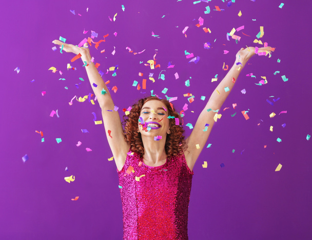 Happy young woman with confetti on color background - Foto, Imagem