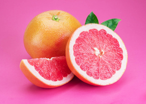 Grapefruits and grapefruit slices isolated on pink background. - Foto, immagini