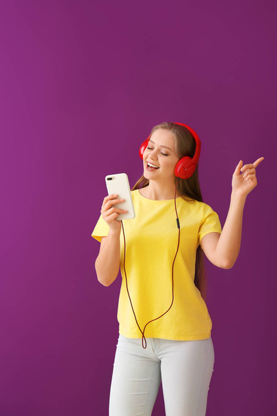 Όμορφη νεαρή γυναίκα που ακούει μουσική με φόντο το χρώμα - Φωτογραφία, εικόνα