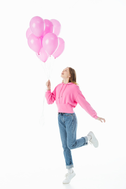 celý pohled na šťastné dospívající děvče, které se dívá na růžové balóny izolované na bílém - Fotografie, Obrázek