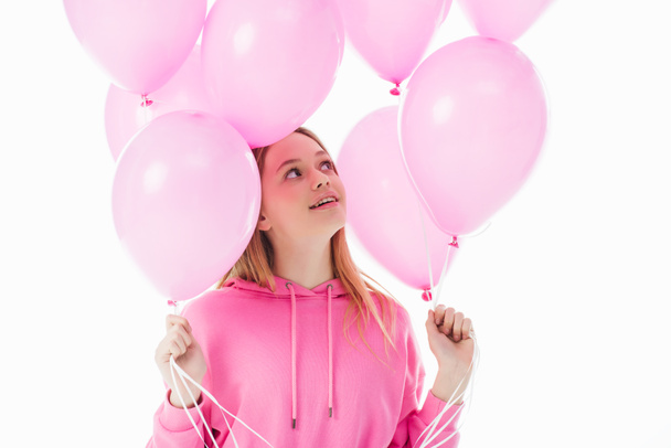 glückliches Teenager-Mädchen sieht rosa Luftballons isoliert auf weiß - Foto, Bild