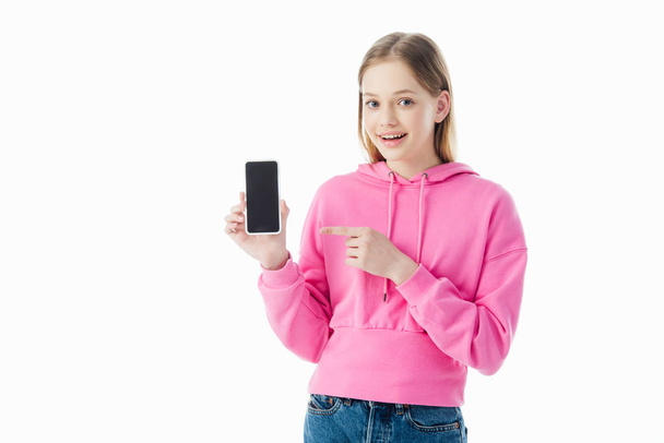 adolescente feliz en sudadera con capucha rosa apuntando con el dedo al teléfono inteligente aislado en blanco
 - Foto, imagen