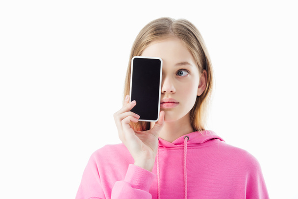 teenage girl in pink hoodie holding smartphone with blank screen in front of face isolated on white - Foto, Bild