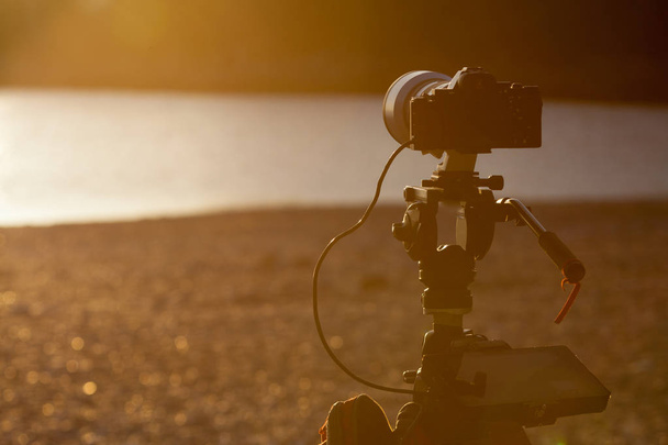 Kamera DSLR sahilde tripod yakalama gün batımı üzerinde set. - Fotoğraf, Görsel