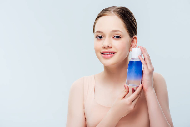 pretty teenage girl holding blue lotion isolated on grey - Foto, afbeelding