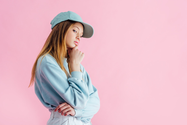 thoughtful sad pretty teenage girl in cap isolated on pink - Photo, Image