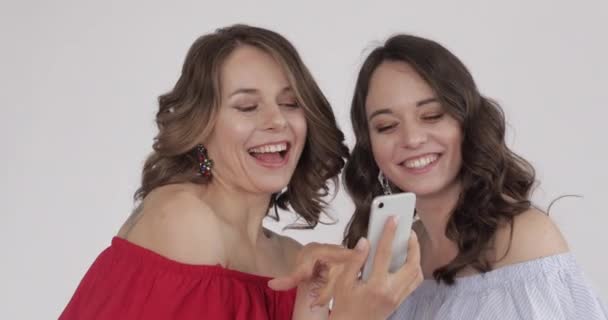 Dwie ładne kobiety patrząc na telefon i wybierając najlepsze selfie - Materiał filmowy, wideo