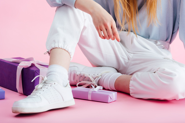 cropped view of teenage girl sitting near presents on pink - Foto, Bild