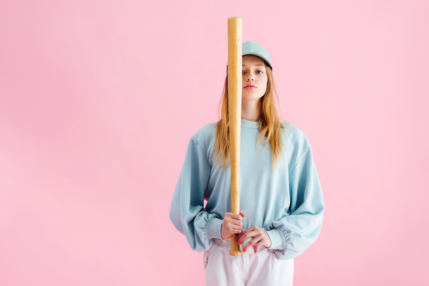 pretty teenage girl in cap holding baseball bat isolated on pink - Foto, afbeelding