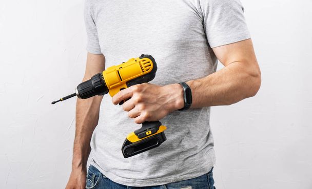 Construction: A man is holding a yellow electric screwdriver. - Φωτογραφία, εικόνα