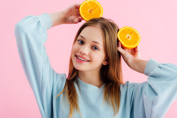 boldog szép tizenéves lány narancssárga felét a fejét izolált rózsaszín - Fotó, kép