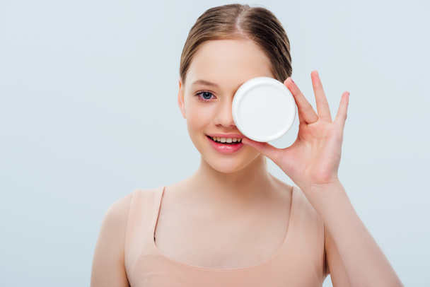 happy teenage girl with obscure face holding cosmetic cream isolated on grey - Φωτογραφία, εικόνα