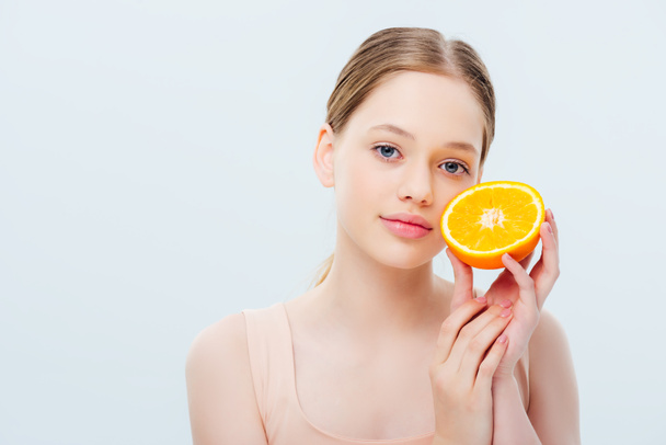 pretty smiling teenage girl holding ripe orange half isolated on grey - Photo, Image