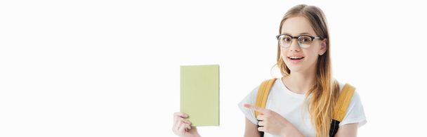улыбающаяся школьница с рюкзаком, указывающая пальцем на книгу, изолированную на белом, панорамном снимке
 - Фото, изображение