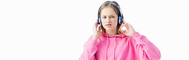 upset teenage girl touching headphones on head isolated on white, panoramic shot - Foto, imagen