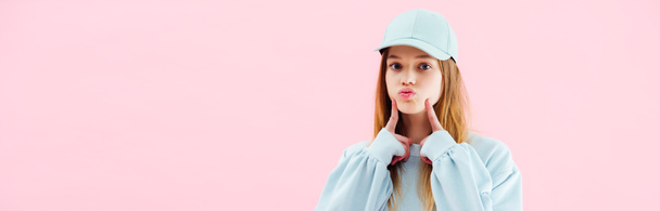 panoramic shot of pretty teenage girl in cap grimacing isolated on pink - Foto, Imagem