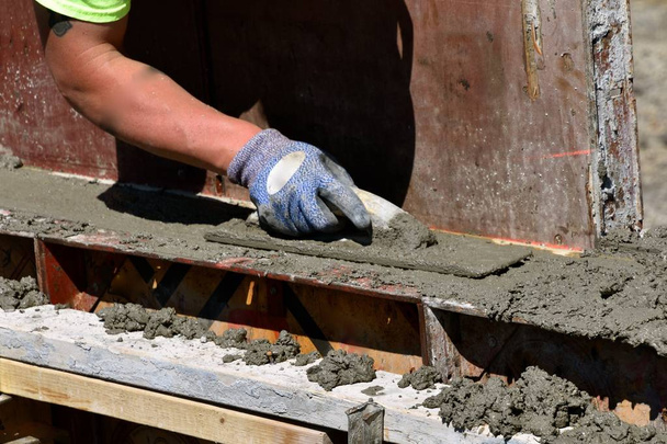 Бетонний працівник накидає мокрий бруд (бетон) на підніжки нового будівельного майданчика
. - Фото, зображення