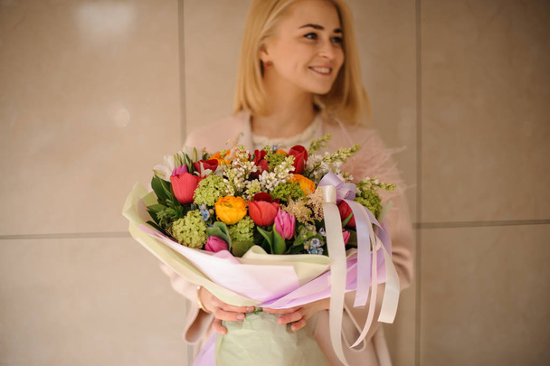 Smiling woman holding bouquet in pink wrapping - Fotó, kép