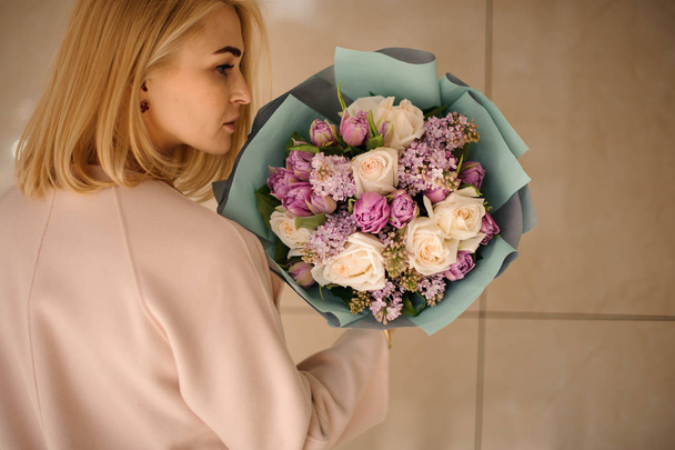 Szőke lány áll, csokor, lila virágok - Fotó, kép