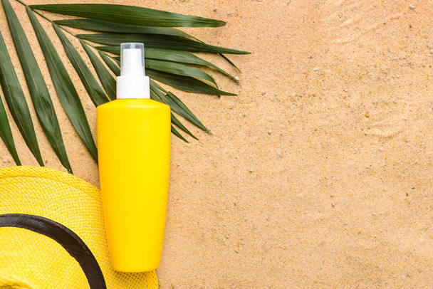 Botella de crema de protección solar y sombrero sobre arena
 - Foto, Imagen