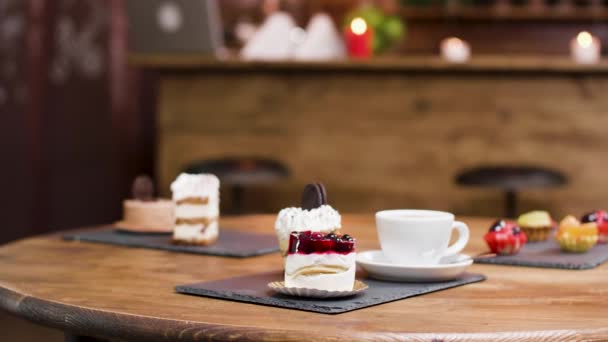 Μια κούκλα με καφέ και φέτες κέικ σε ένα τραπέζι - Πλάνα, βίντεο