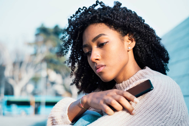 Zwarte vrouw het houden van mobiele telefoon buiten - Foto, afbeelding