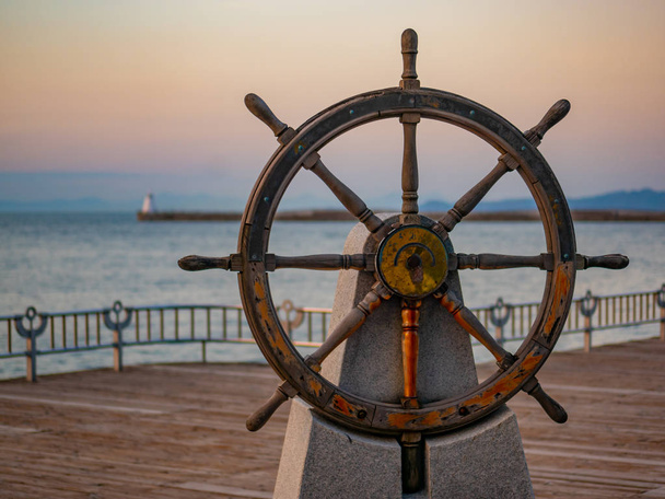 Kapitäne am Steuer oder Ruder eines alten hölzernen Segelschiffs im Hafen bei Sonnenuntergang - Foto, Bild