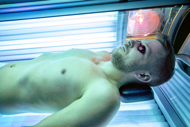 Attractive muscular man in a sunbed - Фото, изображение
