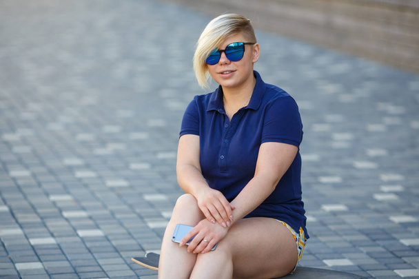 stylish girl plus size sitting on a longboard - Foto, afbeelding