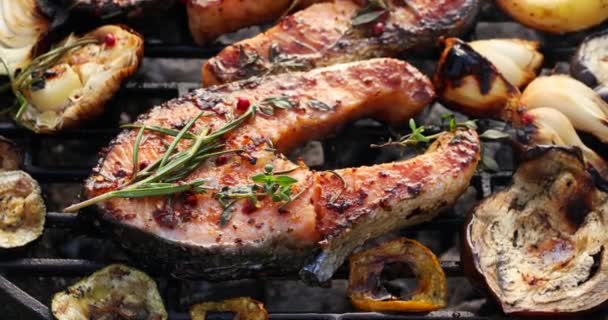 Grillezett hal, grillezett lazac steak azzal a kiegészítéssel, rozmaring, aromás fűszerek és zöldségek a grill lemez a szabadban, közeli, 4k. Grillezett tengeri ételek - Felvétel, videó