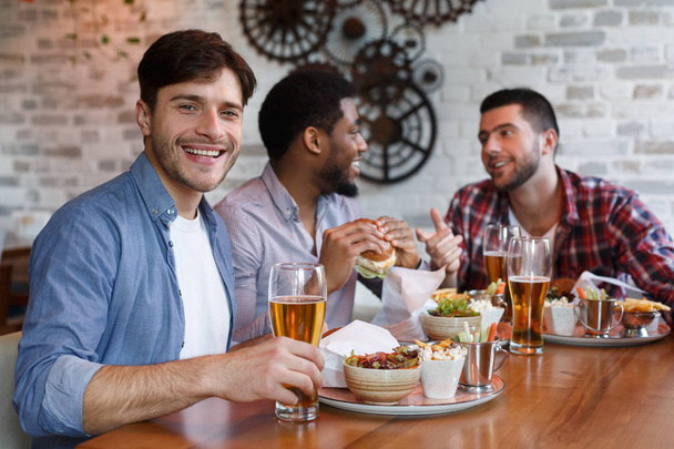 Diverse Friends Eating Burgers And Drinking Beer In Pub - Fotó, kép