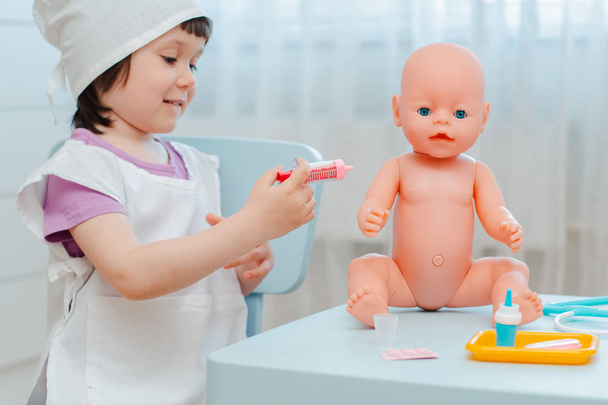 Bambina 3 anni in età prescolare giocare medico con la bambola. Il bambino fa un giocattolo per iniezione
. - Foto, immagini